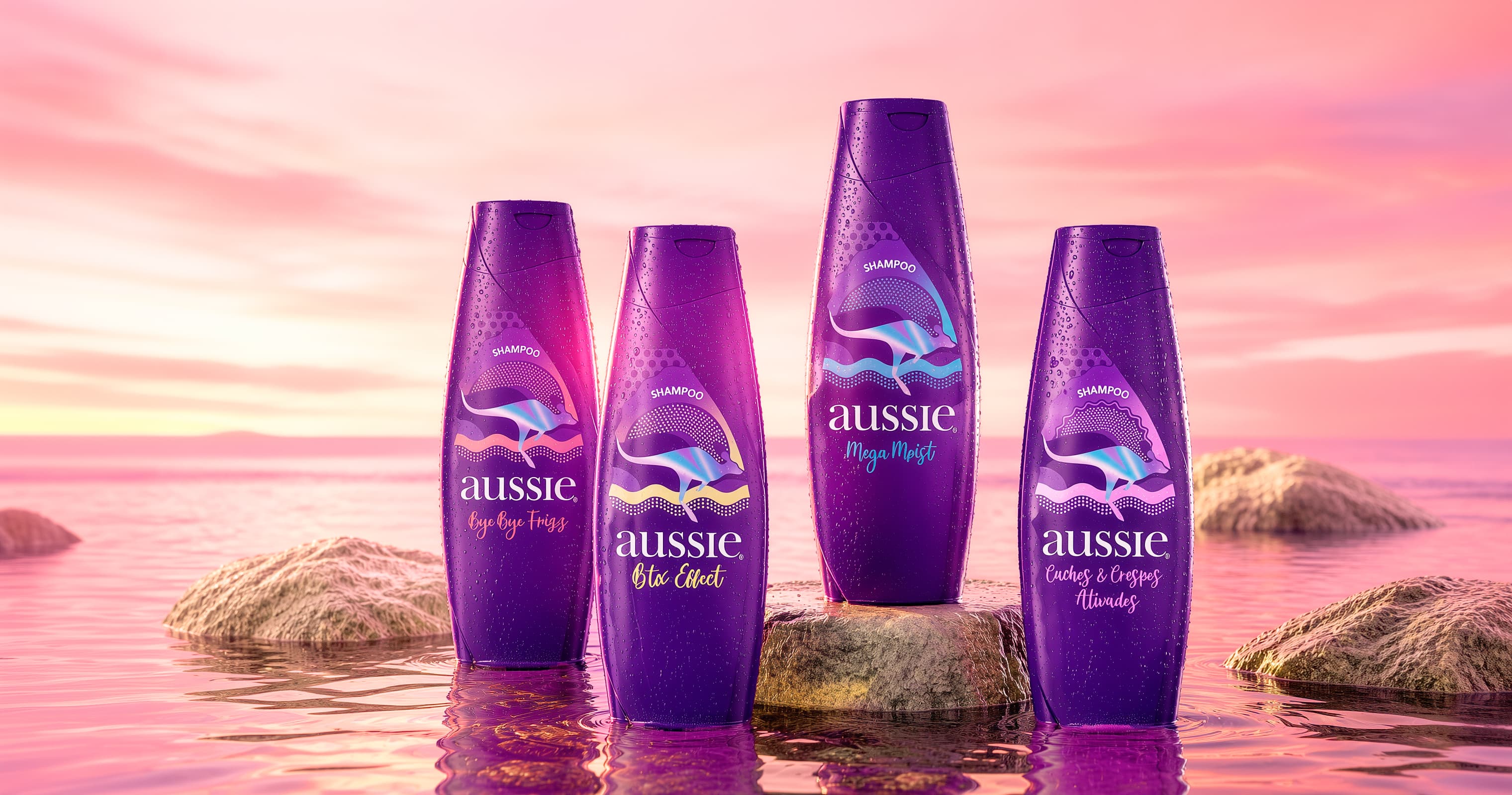 Cuatro envases de shampoo Aussie sobre piedras en el agua, con el cielo rosado al atardecer.